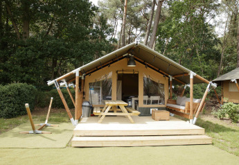 Safari-Zelt-Lodge mit Holzterrasse, Sitzbank, Picknicktisch und Waldkulisse für entspannten Urlaub.