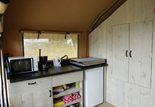 Kleine Küchenzeile im Safari-Zelt bei Costa Kabrita, Niederlande, mit Mikrowelle und Wasserkocher.