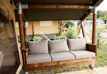 Houten bank met beige kussens bij een safaritent op Costa Kabrita in Nederland, buitenopstelling.