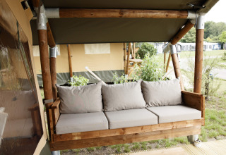 Comfortabele houten zitbank met beige kussens bij een safaritent aan Costa Kabrita in Nederland.