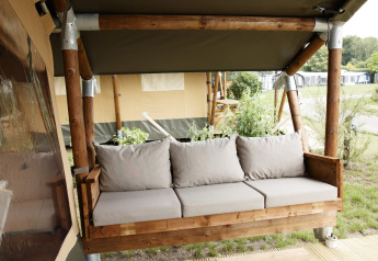 Udendørs lounge med træramme og beige puder på en safaritelt-lodge ved Costa Kabrita i Holland.