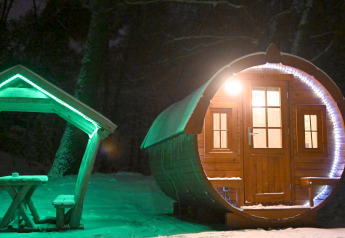 Tiny barrel-shaped house 'Wijnvat' lit up at night with snow, Costa Kabrita, the Netherlands.