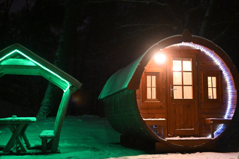 Kleine, fassförmige Holzhütte 'Wijnvat' mit Lichtern und Schnee bei Nacht, Costa Kabrita, Niederlande.