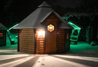 Finse Kota tiny house bij Costa Kabrita in Nederland, ’s nachts sfeervol verlicht met besneeuwde omgeving.