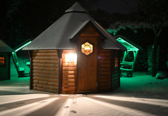 Finse Kota tiny house bij Costa Kabrita in Nederland, sfeervol verlicht in de sneeuw tijdens de nacht.
