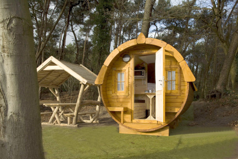 Une petite maison ronde nommée Wijnvat à Costa Kabrita aux Pays-Bas, entourée de forêt et de bancs.