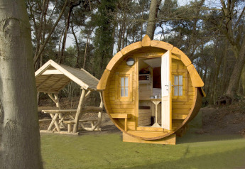 Et rundt træhus kaldet Wijnvat ved Costa Kabrita i Holland, omgivet af skov og picnicområde.