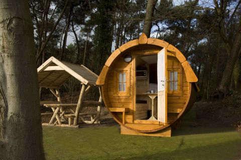 Een rond houten huisje genaamd Wijnvat, gelegen bij Costa Kabrita in Nederland, met bos en zithoek.