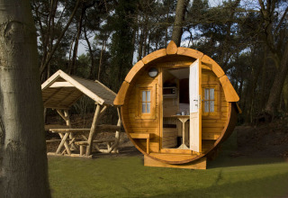 Een rond houten huisje genaamd Wijnvat, gelegen bij Costa Kabrita in Nederland, met bos en zithoek.