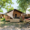 Safaritent Villatent Outback met houten veranda en hangmat, omgeven door bomen op een groene camping.