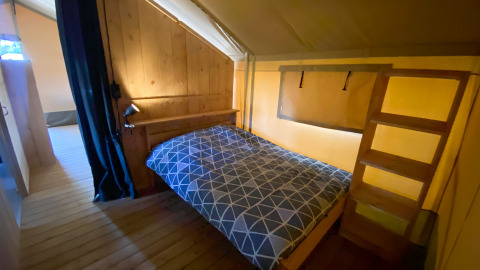 Interno di una tenda safari con letto matrimoniale e pareti in legno al Camping de Tolbrug nei Paesi Bassi.