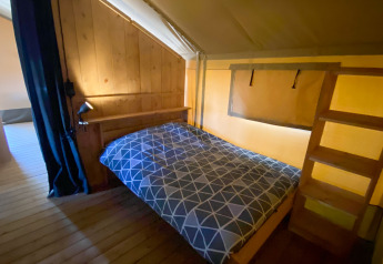 Interno di una tenda safari con letto matrimoniale e pareti in legno al Camping de Tolbrug nei Paesi Bassi.