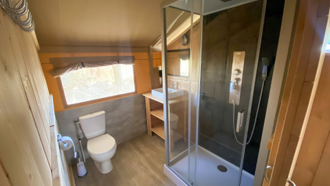 Baño en una tienda safari con ducha, inodoro y lavabo en Camping de Tolbrug, Países Bajos.