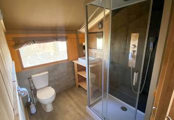 Baño en una tienda safari con ducha, inodoro y lavabo en Camping de Tolbrug, Países Bajos.