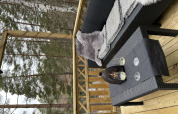 Terrazza esterna presso Stuga Glamping di Småland Miniglamping, Svezia, con divano, tavolo e vista foresta.