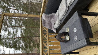 Buitenpatio bij Stuga Glamping in Småland Miniglamping, Zweden, met bank, tafel en uitzicht op het bos.