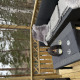 Terraza exterior en Stuga Glamping en Småland Miniglamping, Suecia, con sofá, mesa, copas y vista al bosque.
