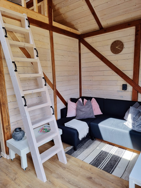 Gezellige leefruimte in Stuga glamping bij Småland Miniglamping, Zweden, met houten trap en hoekbank.
