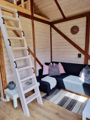 Acogedora sala de estar en Stuga glamping en Småland Miniglamping, Suecia, con escalera y sofá esquinero.