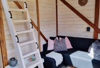 Gezellige leefruimte in Stuga glamping bij Småland Miniglamping, Zweden, met houten trap en hoekbank.