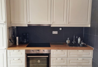 Modern white kitchen with wooden countertop, stove, and sink in a lodge at Stuga Glamping, Småland, Sweden.