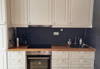 Cucina bianca moderna con piano in legno, forno e lavello in una lodge di Stuga Glamping, Småland, Svezia.
