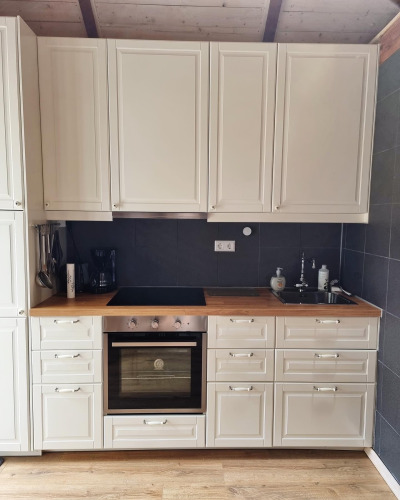 Cocina blanca moderna con encimera de madera, horno y fregadero en un lodge de Stuga Glamping en Suecia.