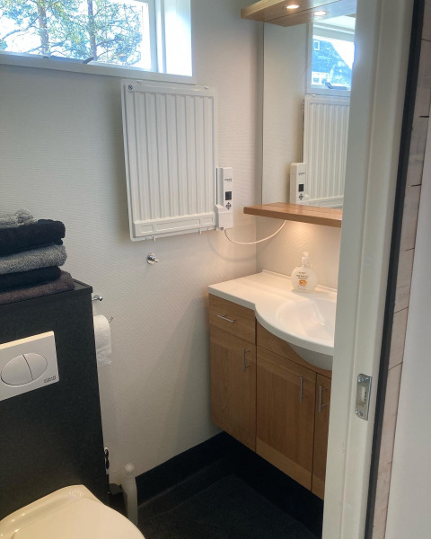 Kleine badkamer met lavabo, spiegel, radiator en raam bij Stuga glamping, Småland Miniglamping, Zweden.