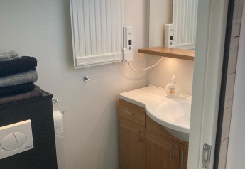 Pequeño baño con lavabo, espejo, radiador y ventana en Stuga glamping, Småland Miniglamping, Suecia.