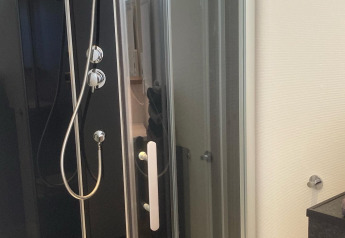 Doccia moderna con box in vetro presso Stuga glamping allo Småland Miniglamping in Svezia, stile luminoso e chic.