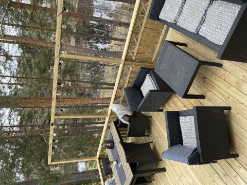Buitenterras bij Stuga glamping van Småland Miniglamping in Zweden, met tuinmeubels en boszicht.