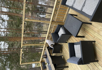 Terraza exterior en Stuga glamping de Småland Miniglamping en Suecia, con muebles de jardín y vista forestal.