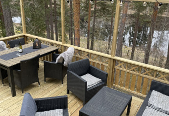 Udendørs terrasse ved Stuga glamping på Småland Miniglamping i Sverige med havemøbler og skovudsigt.