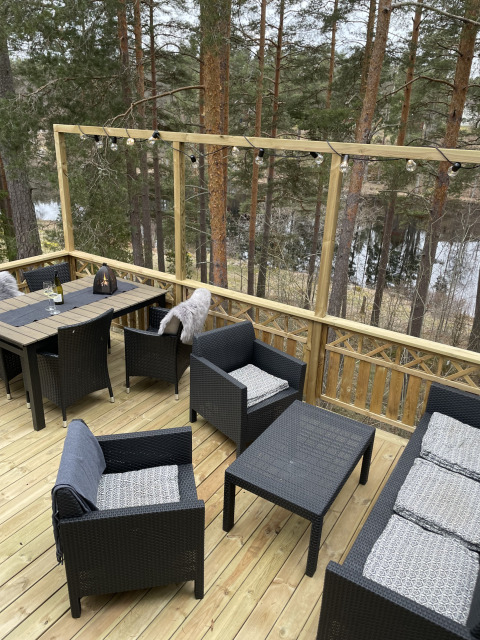 Terrasse von Stuga Glamping bei Småland Miniglamping in Schweden mit Gartenmöbeln und Waldblick.
