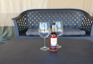 Bouteille de vin et deux verres sur une table devant un banc dans Safari tent, ambiance détente.