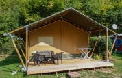 Tienda safari con terraza de madera y muebles exteriores en Camping Bockenauer Schweiz, Alemania, junto al bosque.