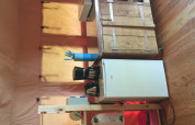 Compact kitchen area in a safari tent, featuring a mini fridge, coffee maker, wooden cabinet and utensils.