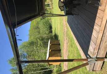 Vista desde la terraza de una tienda safari en Camping Bockenauer Schweiz, con madera y paisaje verde.
