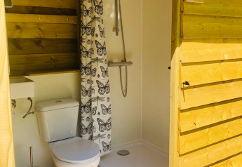 Baño privado en tienda safari con inodoro, ducha y cortina de mariposas en Camping Bockenauer Schweiz.