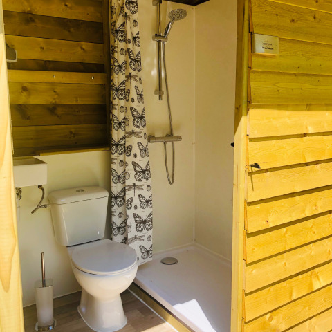 Baño privado en tienda safari con inodoro, ducha y cortina de mariposas en Camping Bockenauer Schweiz.