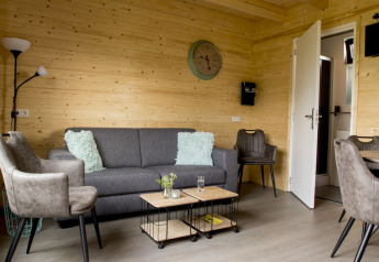 Stue i træhytte på Vakantiehuisje hooiberg, Camping Nieuw Romalo, med moderne møbler i Holland.