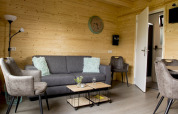 Stue i træhytte på Vakantiehuisje hooiberg, Camping Nieuw Romalo, med moderne møbler i Holland.