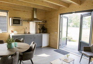 Modernes Ferienhausküche und Essbereich mit Holzwänden, Blick auf Terrasse, Camping Nieuw Romalo, Niederlande.