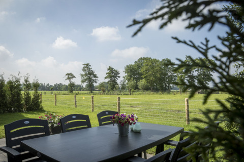 Blick von einer Terrasse mit Tisch und Stühlen im Vakantiehuisje Hooiberg, Camping Nieuw Romalo, Niederlande.