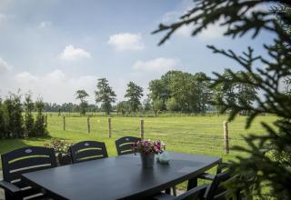 Blick von einer Terrasse mit Tisch und Stühlen im Vakantiehuisje Hooiberg, Camping Nieuw Romalo, Niederlande.