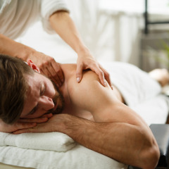Een man krijgt een ontspannende massage in een vakantiepark met luxe glampingaccommodaties en spa.