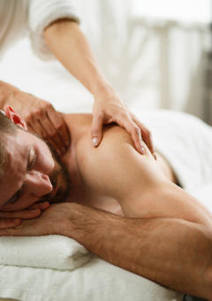 En mand får massage på et spa i en feriepark med luksuriøse glampingmuligheder og afslappende atmosfære.