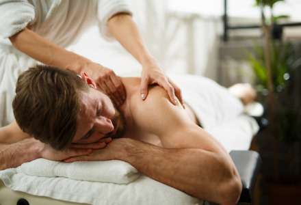 A man enjoys a relaxing massage at a holiday park offering luxury glamping accommodations and spa services.