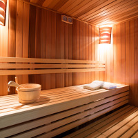 Wooden sauna with bucket and towels under warm lights, pictured near Voorthuizen, Gelderland, Netherlands.