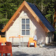 Lille træhytte med orange stole og bord foran, omgivet af skov, på Kabouterhuisje-lodge.